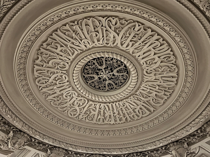An intricately carved stone circle with lettering around a center emblem with four lyres