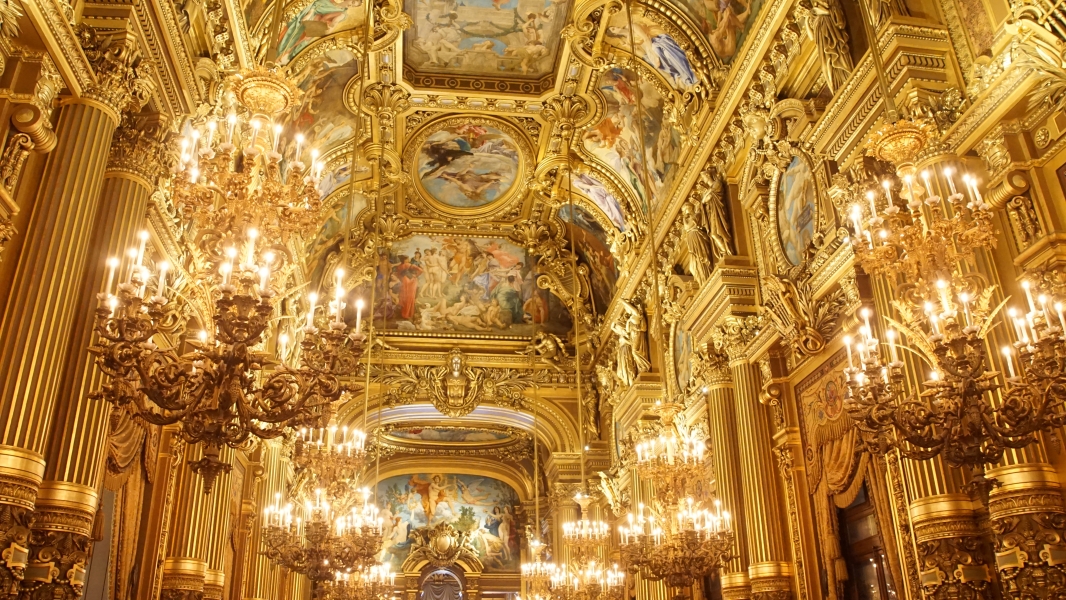 Gold trim walls with paintings and rich detail in a high-ceilinged hall