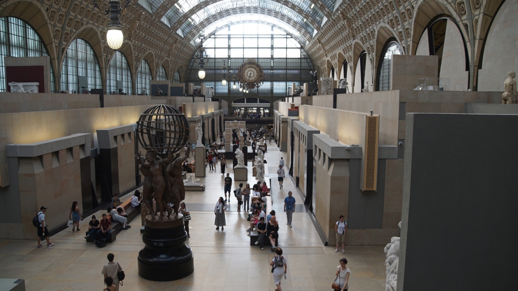Sculptures are on display below a large arched roof with skylights