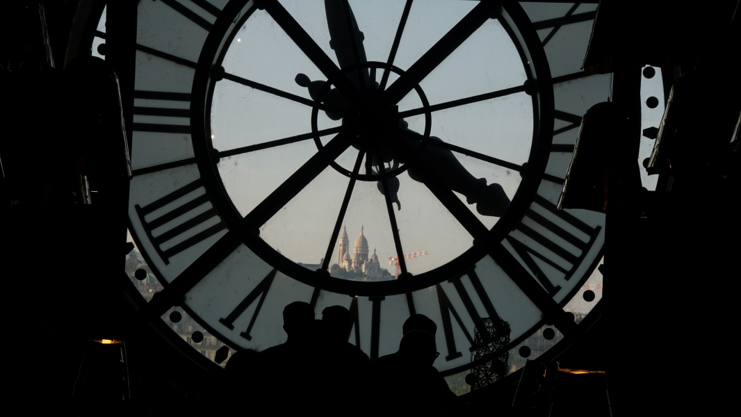 A white church is visible looking out through the glass of an outward facing clock