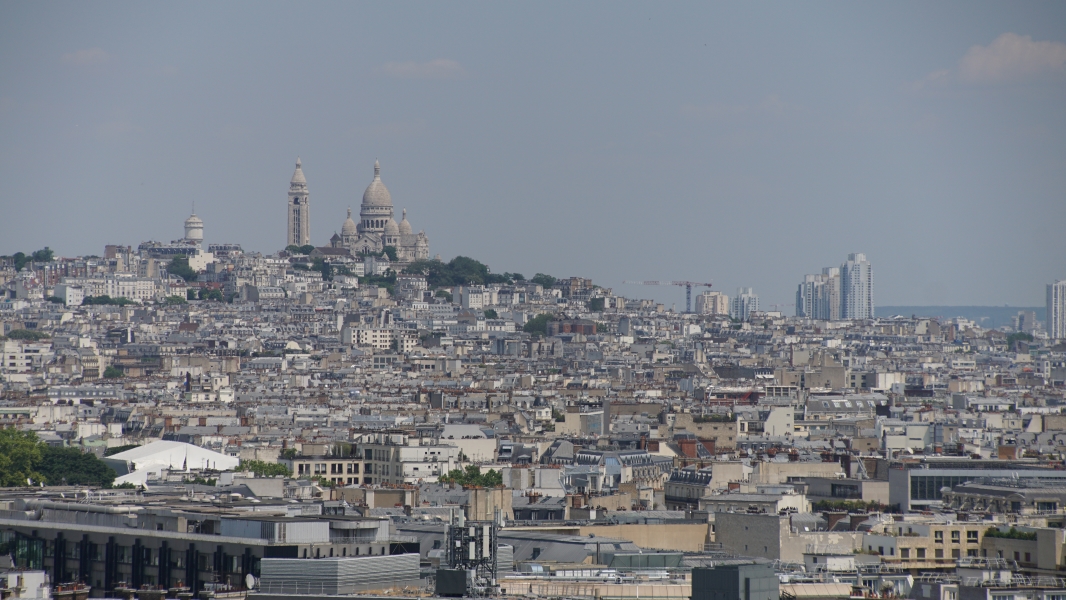 A white church stands on a hill above a sprawling city
