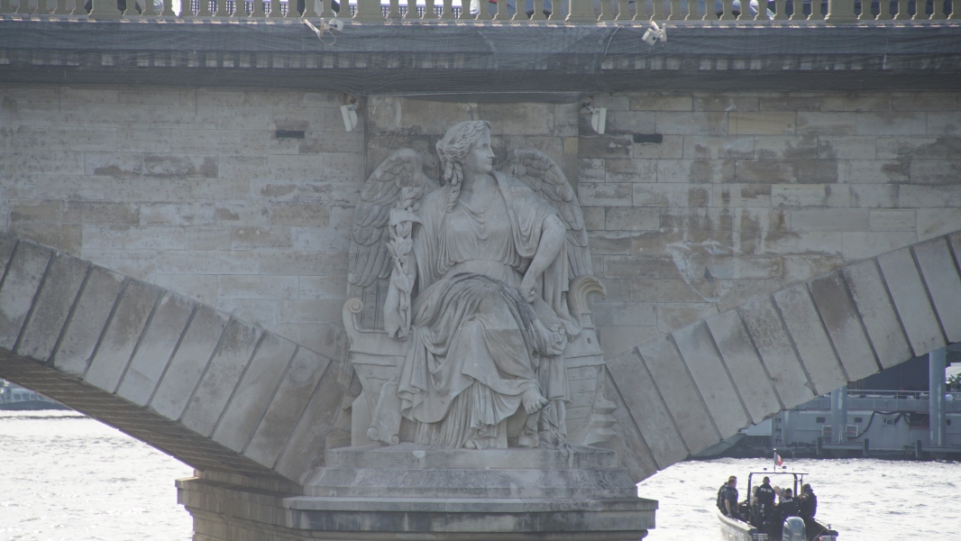 A detailed sculpture of a women on the side of a stone arched bridge