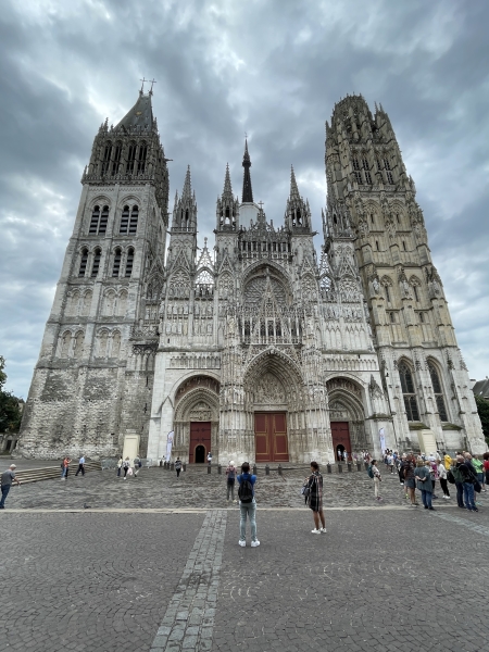 A large stone façade with two towers and three huge doors below a rose window all covered with ornate statues and carvings