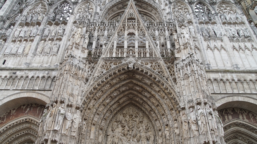 White stone statues and carvings above the entry to a large cathedral