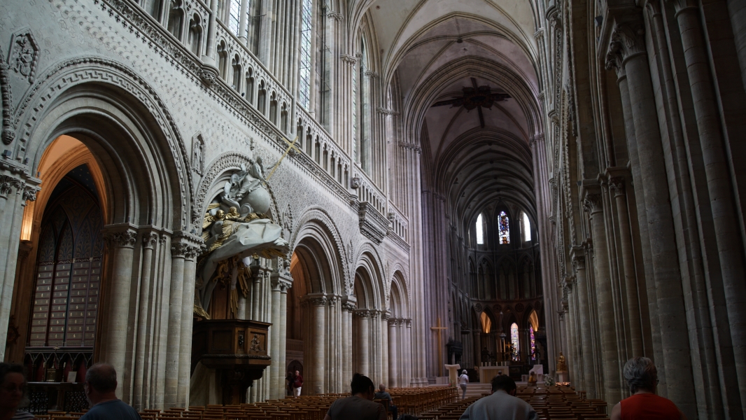 Soft light filters through high windows into the interior of the tall center nave of a gothic style cathedral