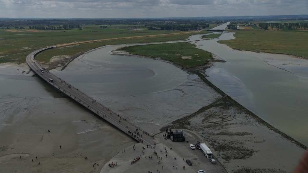 A road and bridge curve through and over tidal sands and flat grasslands