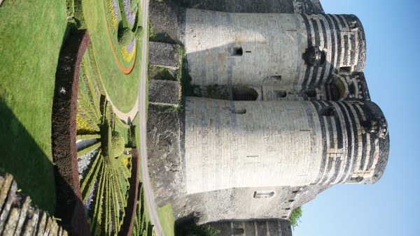 Two large towers at the corner of an old fortress stand above manicured gardens