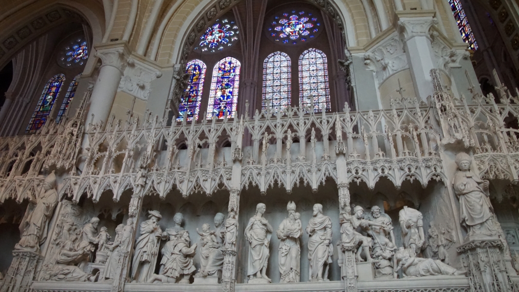 A series of detailed bright white sculptures fill niches in a screen wall