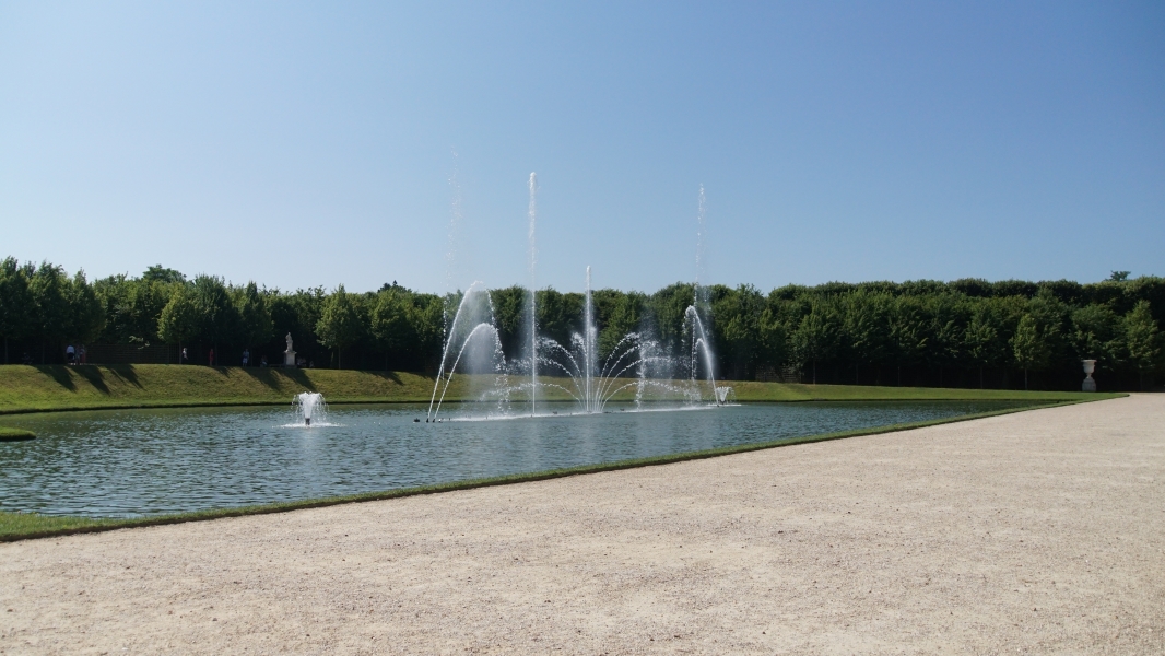 A large pond with several fountains shooting water into the air creating different patterns
