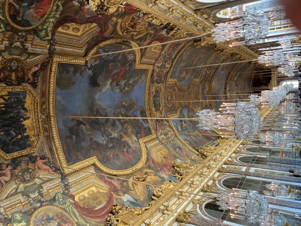ICrystal chandeliers hang from a painted arch ceiling with gold trim above windows on the right and mirrors on the left