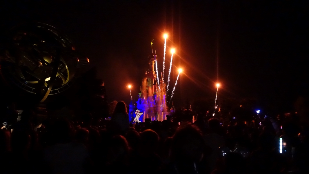 Fireworks light up the crowd as a projection of Simba from the Lion King shows on the front of a castle