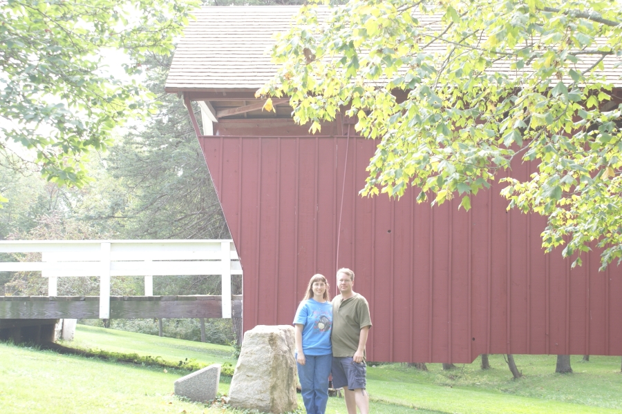James and Julie standing next to a red painted wooden bridge