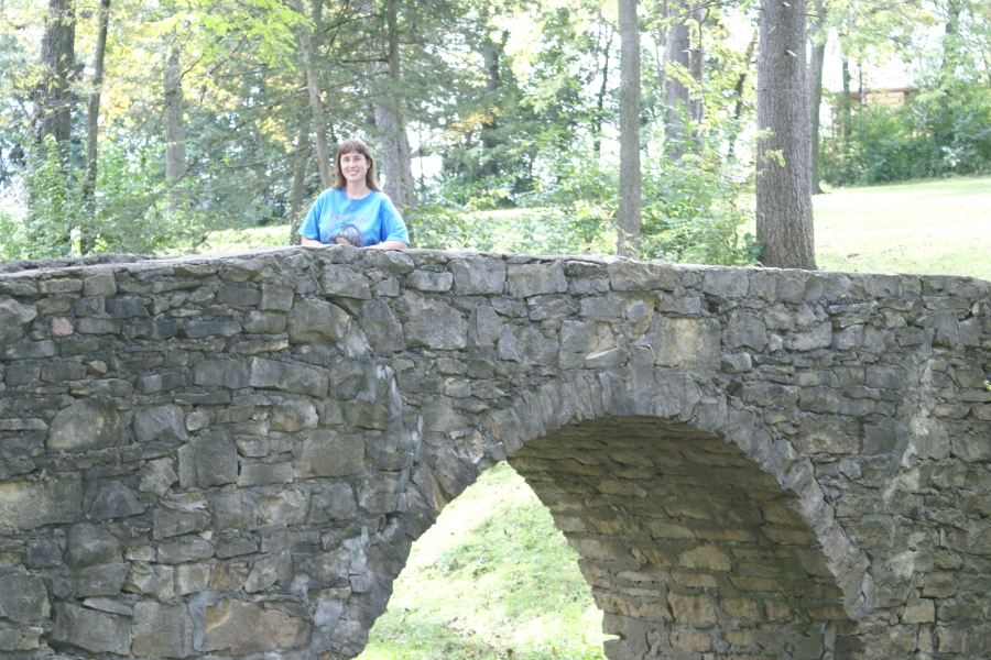 Julie standing on an arched bridge made of stacked stone