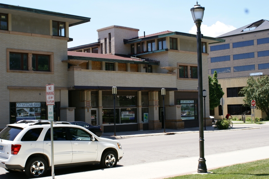 Yellow brick building with glass center between two three-story corner tower elements
