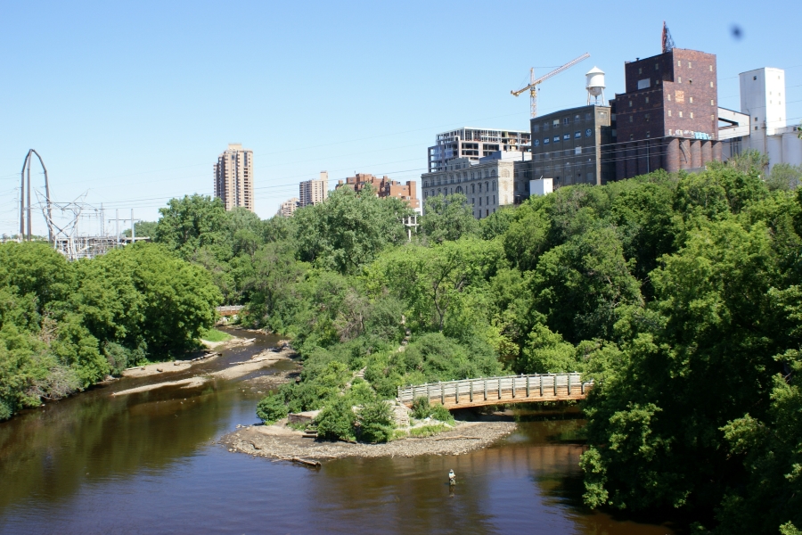 Green trees line the river and sand bars with high rise buildings beyond