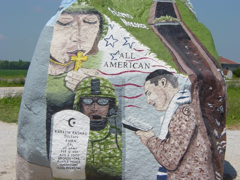 A painted image on a large stone shows three service people of different faiths