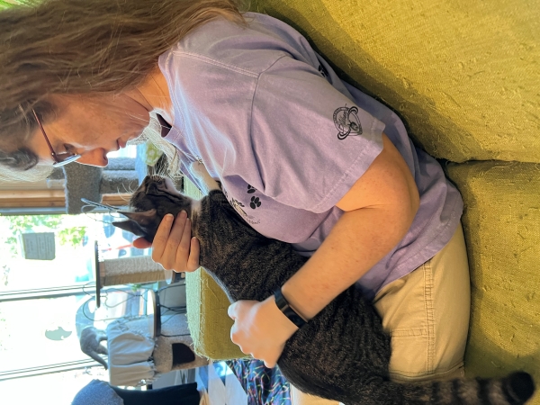 Julie sitting with a cat on her lap extended its nose towards hers