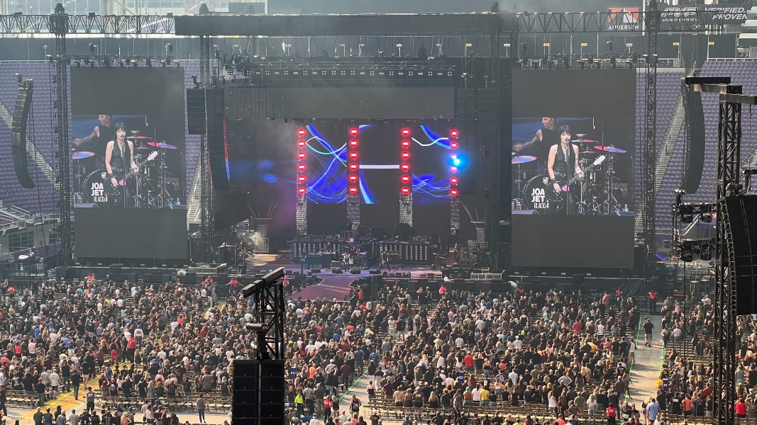 A concert stage with very large digital display screens on each side showing the artist performing