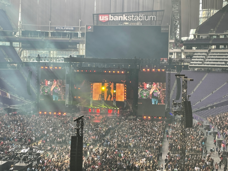 A concert stage with very large digital display screens on each side showing the artist performing