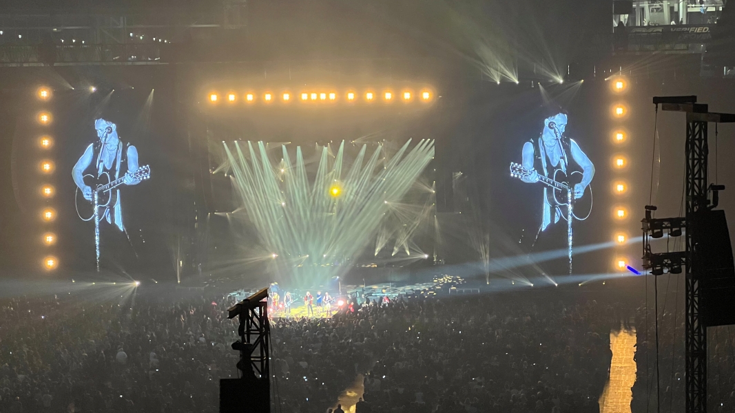 The members of Def Leppard together playing on a portion of the stage projecting into the audience
